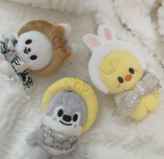 three stuffed animals sitting on top of a white blanket