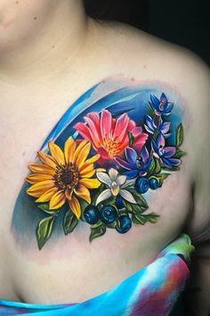 a woman's chest with colorful flowers and leaves painted on the top of it