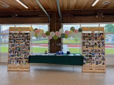 the table is set up in front of two large windows with pictures on it and balloons hanging from them