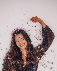 a woman with her arms behind her head covered in confetti