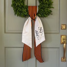 a halloween wreath is hung on the front door with an orange and black striped ribbon