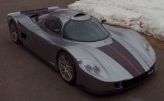 a silver sports car parked on the side of a road next to snow covered ground