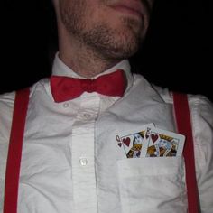 a man wearing red suspenders and a bow tie with playing cards on his chest