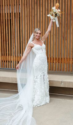 a woman in a wedding dress holding up her bouquet