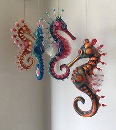 three seahorses hanging from strings on the wall