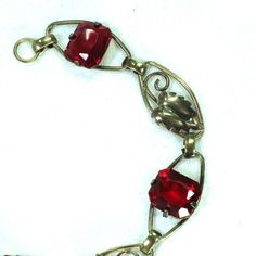 This is part of Chairish’s Costume Jewelry assortment.  1930s Art Deco 12k gold over sterling link bracelet. This delicate offering presents open elliptical links with smooth connectors, alternating heart-shaped leaves with emerald-cut ruby-colored  crystals. The workmanship is simple and meticulous, and the stones are vivid and evocative. Elegant and subtle, but with a hint of exuberance in the ruby crystals, this beauty is equally at home with a white shirt and jeans or a classic LBD. Not sign Vintage Yellow Gold Rectangular Link Jewelry, Vintage Yellow Gold Jewelry With Rectangular Links, Elegant Vintage Charm Oval Link Jewelry, Elegant Jewelry With Vintage Charm And Oval Link, Antique Ruby Jewelry With 17 Jewels, Heirloom Metal Jewelry For Formal Occasions, Heirloom Link Jewelry For Formal Occasions, Heirloom Style Formal Metal Jewelry, Heirloom Metal Jewelry Hallmarked