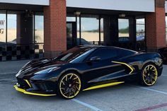 a black and yellow sports car parked in front of a building