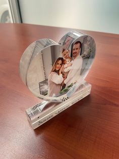 an acrylic heart shaped photo frame on a wooden table with a couple in it