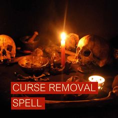 a table topped with skulls and candles in front of a black background that says curse removal spell