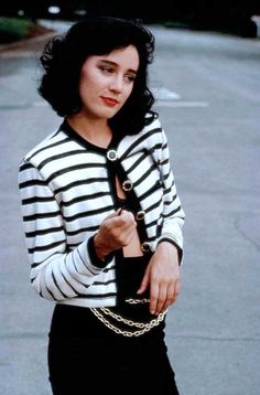 a woman in black and white striped shirt holding a chain around her waist while standing on the street