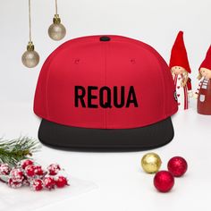 a red and black snapback hat with the word requa on it next to christmas decorations