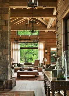 an open living room with stone walls and wood ceilinging, along with large windows