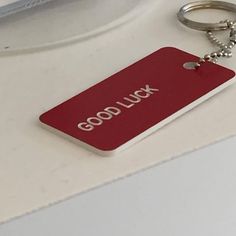 a close up of a red tag on a white surface with a beaded keychain