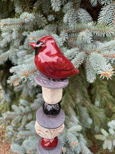 a red bird sitting on top of a stack of three small ceramic birds perched on top of each other