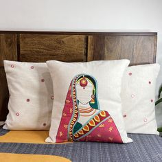 three pillows on a bed with an image of a woman in red and green, sitting next to each other