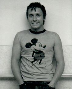 a black and white photo of a man in mickey mouse shirt