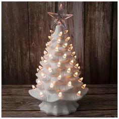 a white ceramic christmas tree with lights on it's base and a star hanging from the top