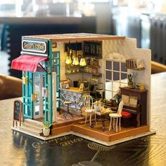 a doll house with furniture and accessories on a table in front of a coffee shop