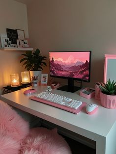 a desk with a computer, keyboard and plant on it in front of a pink wall