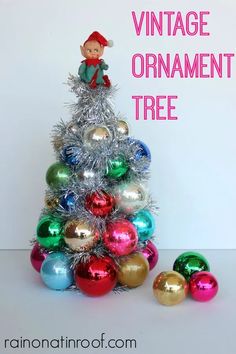 an ornament christmas tree with tinsel ornaments and a elf figurine on top