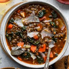 a bowl filled with lentils, carrots and spinach on top of a table