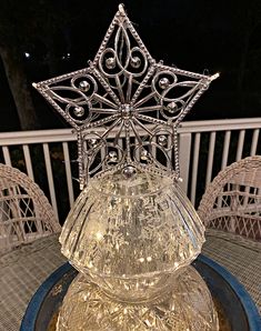 a clear glass candle holder sitting on top of a blue plate with silver filigreets