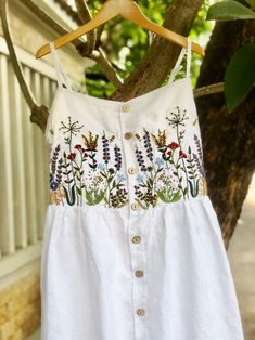 ❤ Item description: - It's a lovely dress like a mini garden with colourful embroidered flowers and bee motifs. - Material: linen, coconut button, hand embroidery. - Environmentally friendly. - This dress is very useful, go with any outfit, that can be used to go to school, go out, go shopping.    It is a perfect gift for yourself or your beloved.  ❤ Care instructions:      The best way to wash embroidery cloth is to put it in soapy water (with a mild detergent and cold water at 86 ºF/30oС) for 20 minutes. Try to not wash the item with other clothing that might cause damage, such as zippers, buttons or different colors. You wash it by hand, and if you have dirty patches on your garment, you can gently rub them, it's best not to rub directly against the embroidery. Rinse with clean water. T Embroidered Dress Diy, Strawberry Butterfly, Dress Hand Embroidery, Mini Forest, Simple Frocks, Hand Embroidery Dress, Handmade Dress, Go To School, Embroidered Clothes