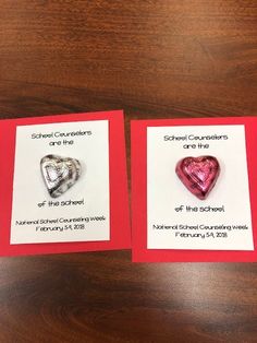 two valentine's day cards with hearts on them sitting on top of a wooden table