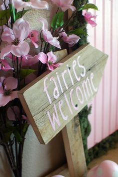 a sign that says fairies welcome with pink flowers