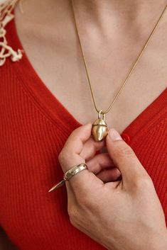 a woman wearing a red sweater holding a gold necklace