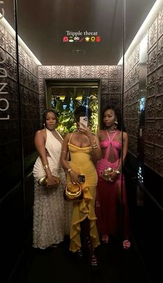 three women are standing in front of an elevator