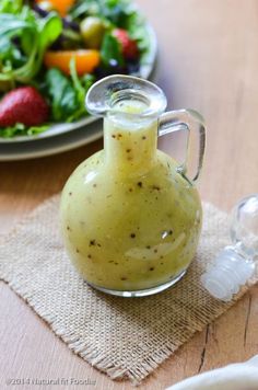 a salad in a glass bottle next to a plate with strawberries