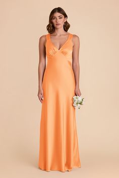 a woman in an orange dress holding a bouquet