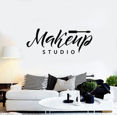 a living room with a white couch and black wall decal that says makena studio