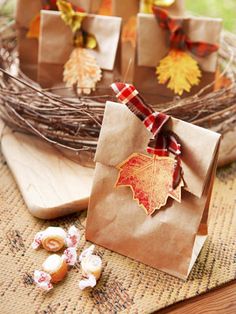 brown paper bags with fall leaves on them sitting on a table next to some candy