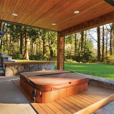 a hot tub sitting on top of a wooden deck next to a stone fire pit