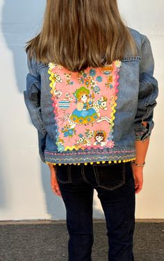 the back of a woman's jean jacket with an image of a cartoon character on it