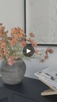 a vase filled with pink flowers sitting on top of a black table next to a book