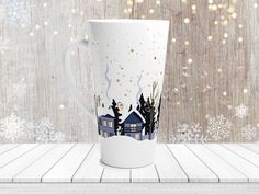 a white coffee cup sitting on top of a wooden table next to snowflakes