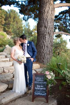 a bride and groom kissing in front of a sign