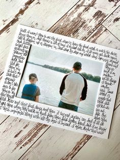 two people standing next to each other in front of a wooden wall with writing on it