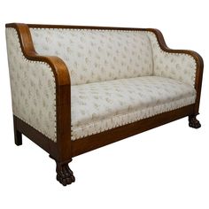 an old fashioned wooden couch with white upholstered fabric and wood trimmings