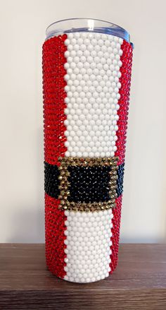 a red, white and black beaded cup sitting on top of a wooden table