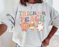 Retro Trick or Teach Halloween Sweatshirt xo Rock a classic fleece pullover with ribbed crew neck, long sleeve cuffs, and a flat hem. Layer it up or wear it on its own for a contemporary streetwear look. ♥ 》 》SIZING 《 《 These are unisex sweaters. They fit true to size. 》 》PLEASE NOTE 《 《 Ships in 2-7 business days. 》 》 ANATOMY OF OUR SHIRTS 《 《 * Brand: Gildan 18000 * 50% cotton, 50% polyester * Pre-shrunk * Classic fit * 1x1 athletic rib knit collar with spandex * Air-jet spun yarn with a soft Fall Tee Shirt Designs, Fifth Grade Teacher Outfits, Athletic Teacher Outfits, Diy Teacher Shirts, Autumn Teacher Outfits, Cute Fall Teacher Shirts, Cricut Teacher Shirts