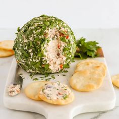 an artichoke cheese ball on a cutting board with crackers and parsley