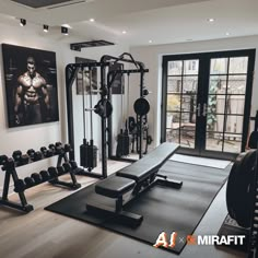 a home gym with exercise equipment in front of large windows and pictures on the wall