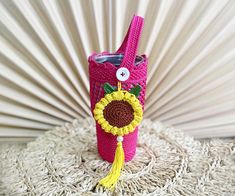 a pink crocheted cell phone case with a sunflower on the front and side