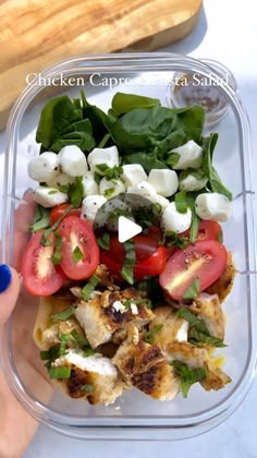 a plastic container filled with chicken, tomatoes and spinach