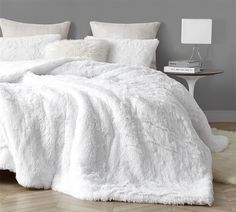 a white bed with fluffy blankets and pillows