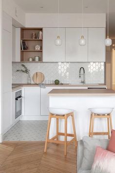 a white kitchen with two stools in front of the counter and an open cabinet